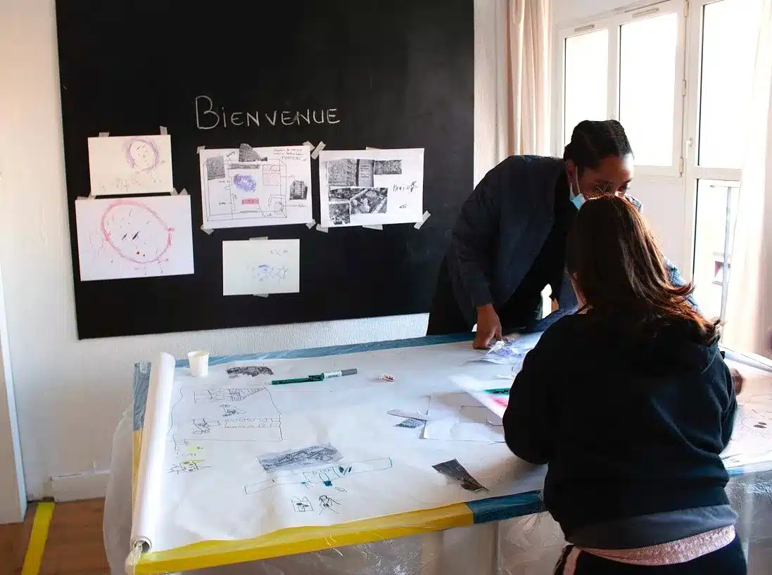 Atelier artistique avec une médiatrice et une enfant dans l'espace d'accueil aménagement dans un appartement de la cité Émile-Dubois pour l'exposition "La vie HLM"