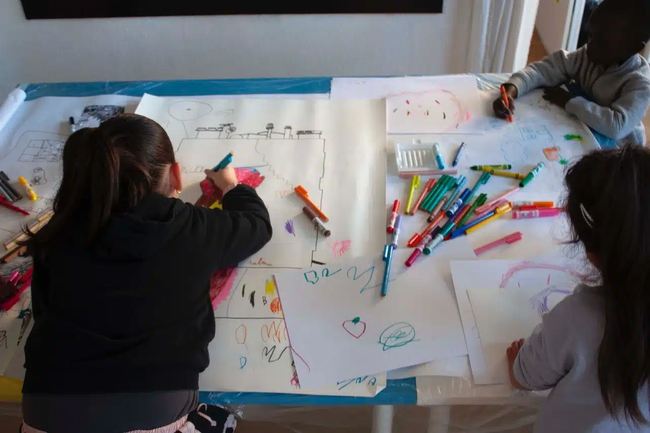 Enfants dessinant durant un atelier artistique lié à l'expo La Vie HLM
