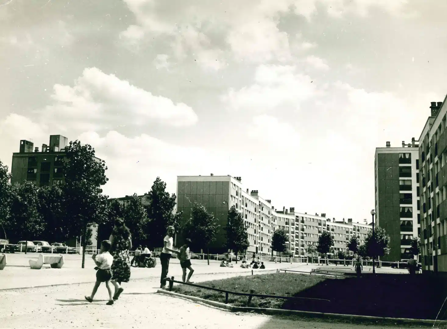 Quelques personnes dans une allée d'une cité HLM. Photographie en noir et blanc