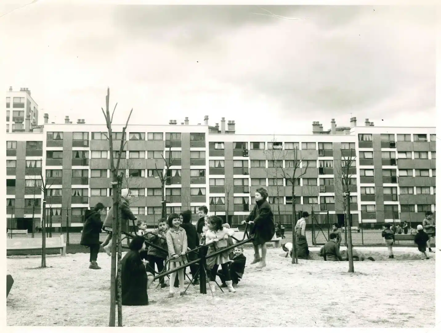 Enfants jouant sur une aire de jeu d'une cité HLM. Photographie en noir et blanc