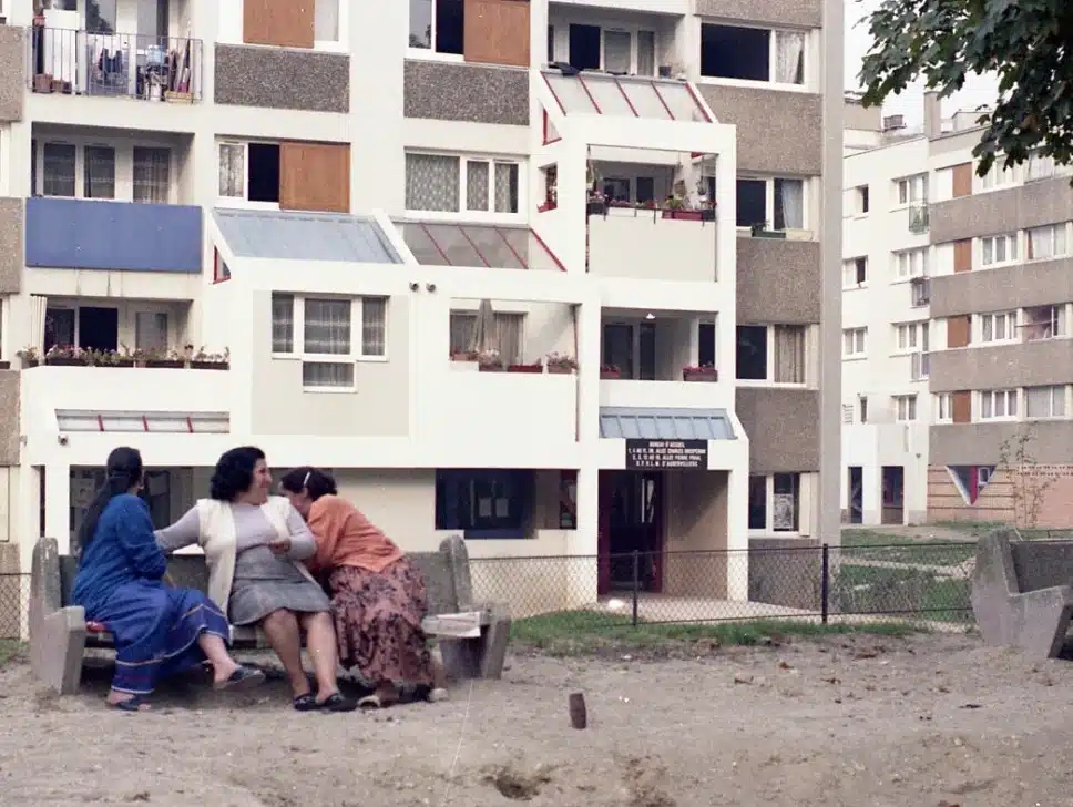 Trois femmes assises sur un banc public devant un bâtiment de cité HLM venant d'être réhabilité
