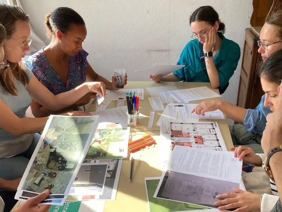 Groupe de personnes étudiant ensemble des documents d'archives, photos et plans