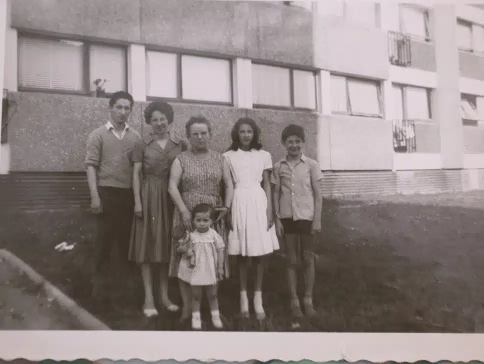 Une famille pose devant un immeuble de cité HLM, photographie en noire et blanc
