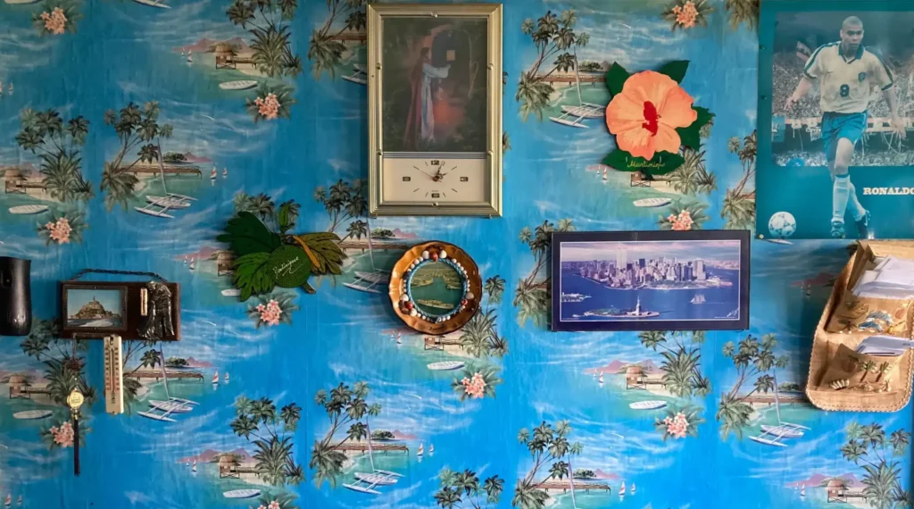détail de l'intérieur d'un appartement, papier peint aux motifs d'îles tropicales, poster, cadres et objets décoratifs
